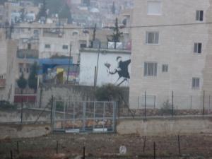Banksy's seminal image of a molotov cocktail launching protester, altered to have him throwing a bouquet of flowers instead, in the West Bank